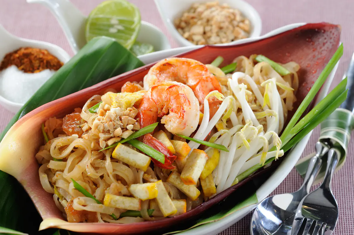 Pad Thai mit Garnelen, Erdnüssen und Limettenscheiben auf einem Teller